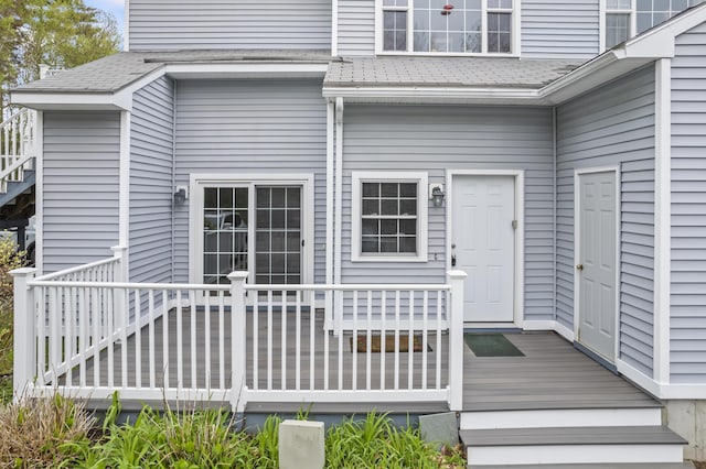 property entrance with a shingled roof and a deck