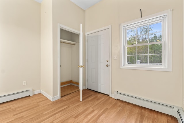 unfurnished bedroom with a baseboard radiator, light wood-style flooring, and baseboards
