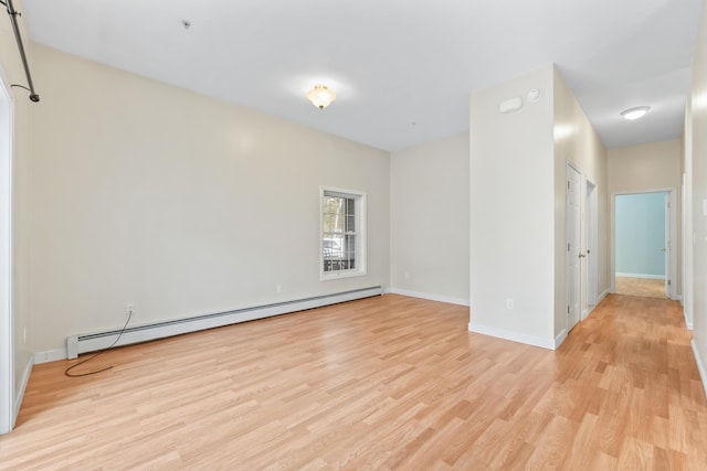 unfurnished room featuring a baseboard heating unit, light wood-type flooring, and baseboards