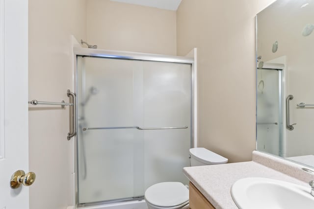 full bath with a stall shower, toilet, and vanity