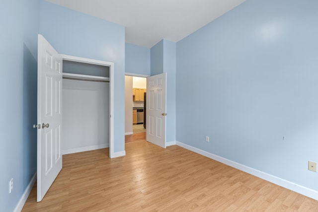unfurnished bedroom featuring light wood-style floors, baseboards, and a closet