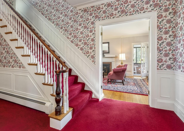 14 Highland St, Portland, ME 04103 - staircase with wallpapered walls, a baseboard heating unit, a wainscoted wall, crown molding, and a brick fireplace