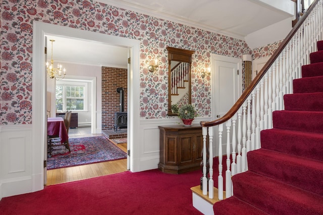 14 Highland St, Portland, ME 04103 - foyer with ornamental molding, stairway, wallpapered walls, a wainscoted wall, and a wood stove