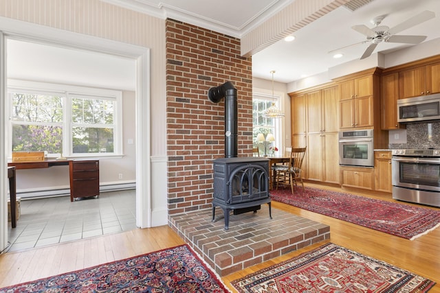 14 Highland St, Portland, ME 04103 - kitchen with appliances with stainless steel finishes, a wood stove, light wood finished floors, baseboards, and pendant lighting