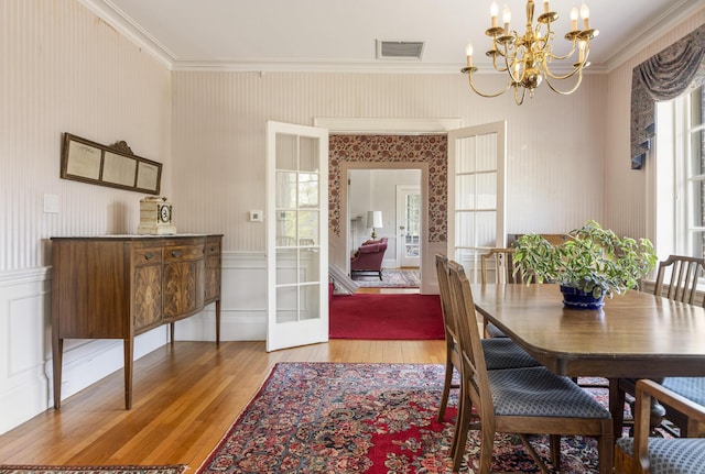 14 Highland St, Portland, ME 04103 - dining space with light wood finished floors, a chandelier, plenty of natural light, crown molding, and a decorative wall