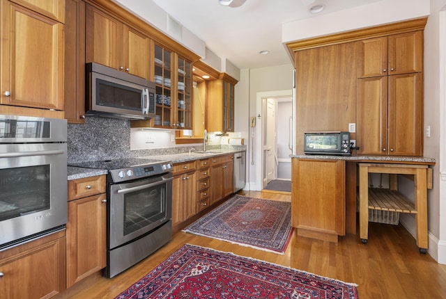 14 Highland St, Portland, ME 04103 - kitchen with stainless steel appliances, a sink, wood finished floors, and brown cabinets