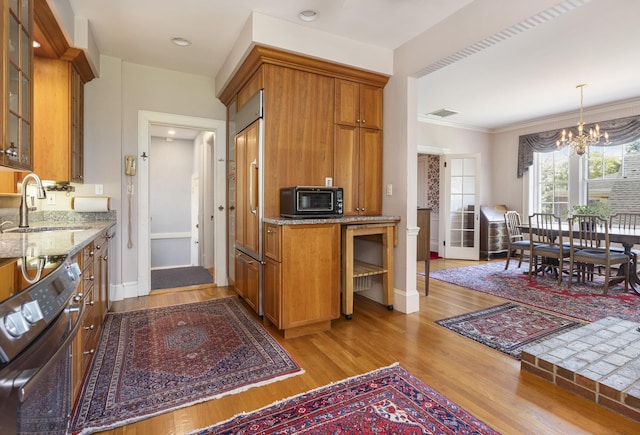 14 Highland St, Portland, ME 04103 - kitchen with a sink, a chandelier, brown cabinets, light stone countertops, and light wood-type flooring