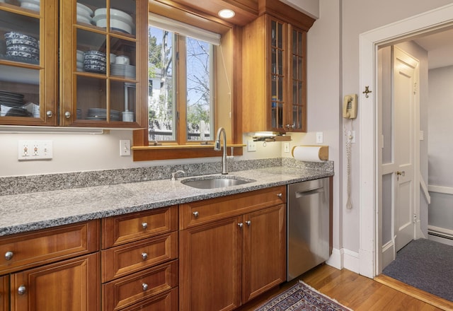 14 Highland St, Portland, ME 04103 - kitchen with stainless steel dishwasher, a sink, light stone countertops, wood finished floors, and glass insert cabinets