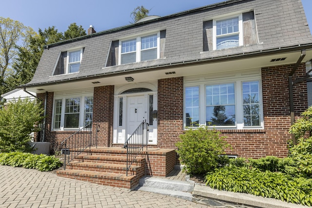 14 Highland St, Portland, ME 04103 - view of front facade featuring mansard roof, brick siding, and a shingled roof
