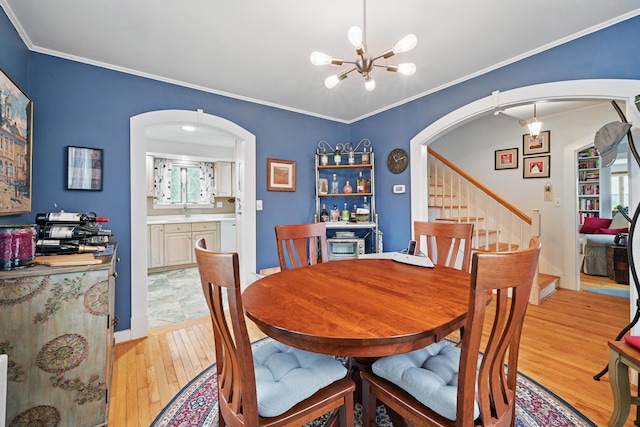 51 Googin St, Lewiston, ME 04240 - dining area featuring arched walkways, a chandelier, light wood finished floors, stairs, and crown molding