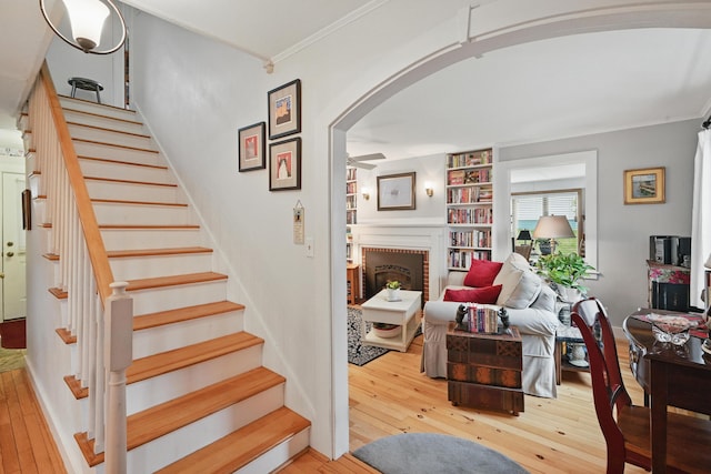 51 Googin St, Lewiston, ME 04240 - staircase featuring arched walkways, hardwood / wood-style floors, ceiling fan, ornamental molding, and a brick fireplace