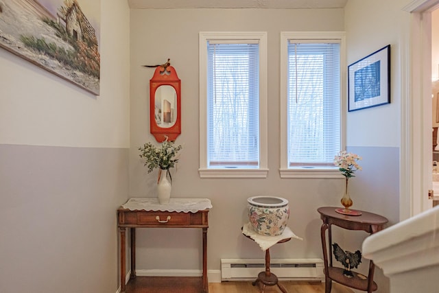 living area featuring a baseboard radiator, wood finished floors, and baseboards