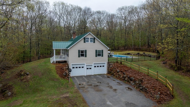 229 Stone Rd, Newfield, ME 04095 - view of home's exterior with asphalt driveway, a garage, a view of trees, a chimney, and metal roof