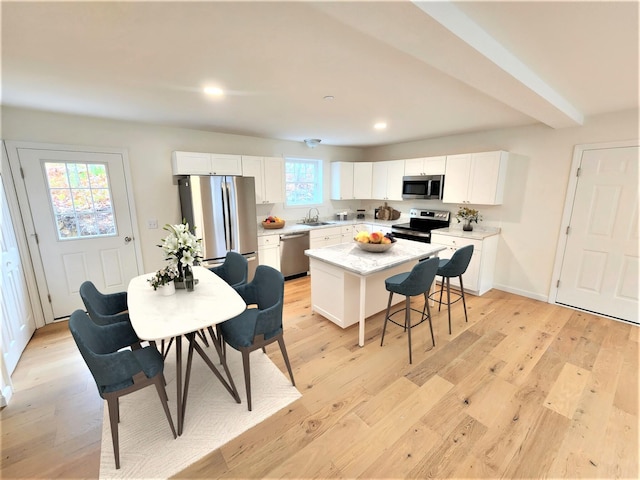 kitchen with a sink, stainless steel appliances, a kitchen island, and white cabinets