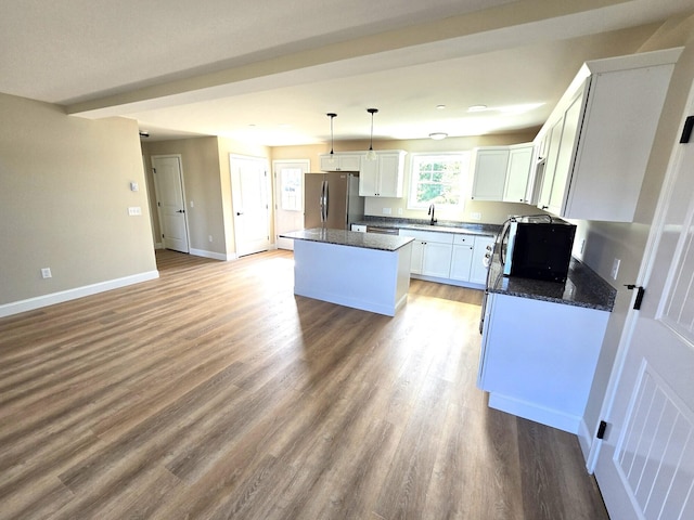 kitchen featuring a center island, a sink, freestanding refrigerator, white cabinets, and baseboards