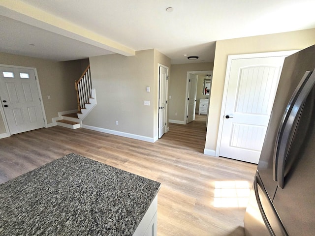foyer featuring light wood-style flooring, baseboards, and stairs