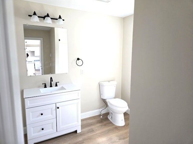 bathroom featuring vanity, toilet, baseboards, and wood finished floors