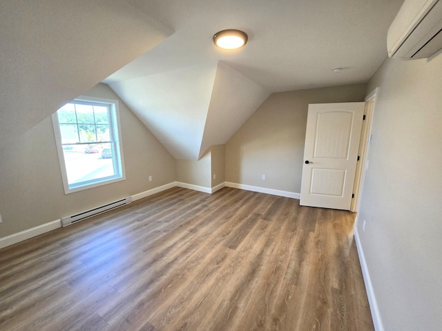 additional living space featuring lofted ceiling, wood finished floors, a wall mounted AC, baseboard heating, and baseboards