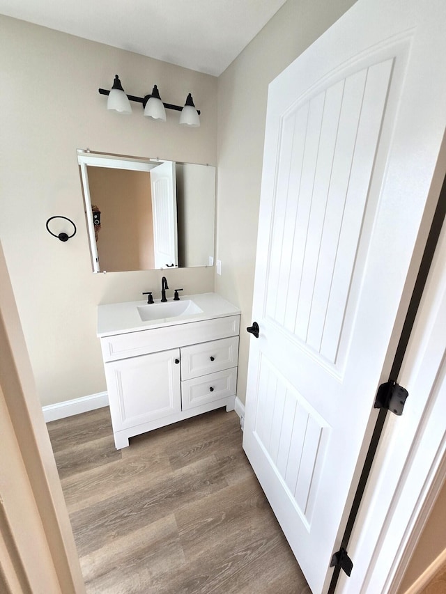 bathroom with baseboards, wood finished floors, and vanity
