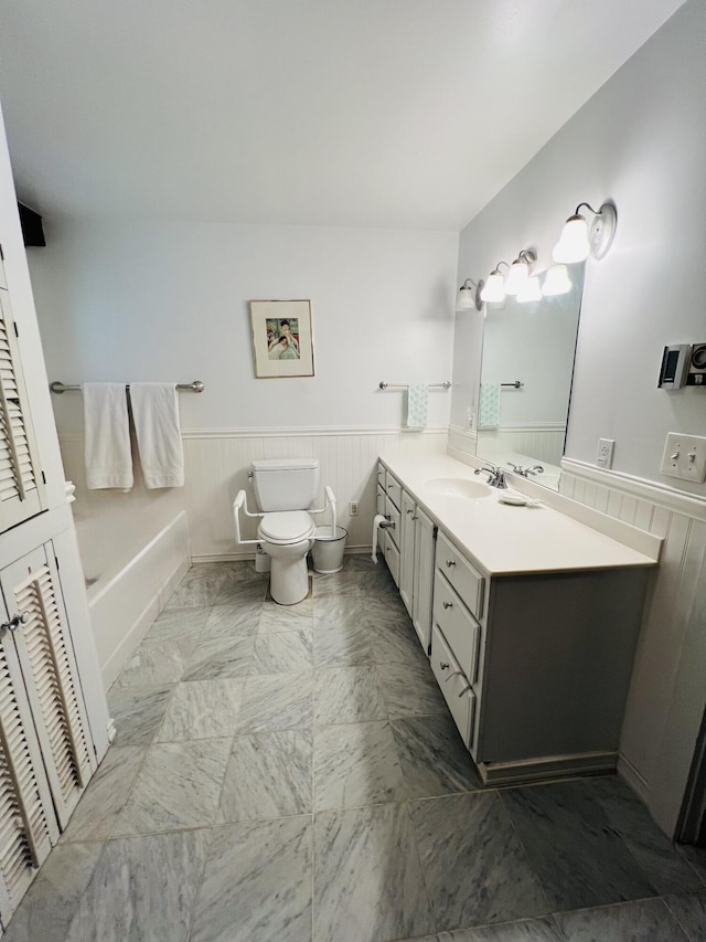 329 Salt Pond Rd, Blue Hill, ME 04614 - bathroom featuring vanity, a wainscoted wall, toilet, marble look tile flooring, and a tub to relax in