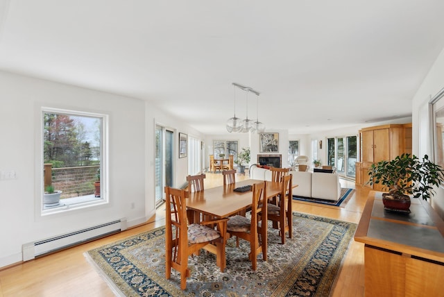 388 High Head Rd, Harpswell, ME 04079 - dining room with baseboard heating, light wood-type flooring, and a glass covered fireplace