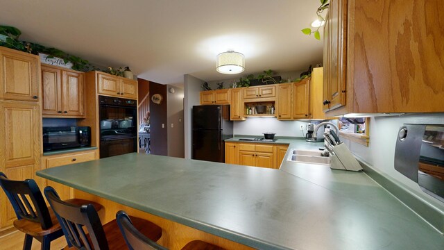 kitchen with black appliances, a sink, a peninsula, and a breakfast bar