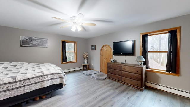 bedroom with a baseboard radiator, light wood-style floors, and ceiling fan