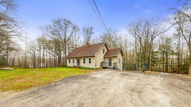 view of front of home with a chimney, a shingled roof, and driveway