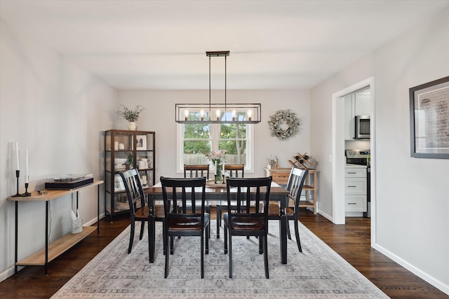 dining room with a chandelier, dark wood finished floors, and baseboards