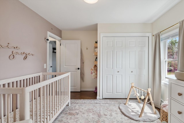 bedroom featuring a closet, multiple windows, wood finished floors, and a crib