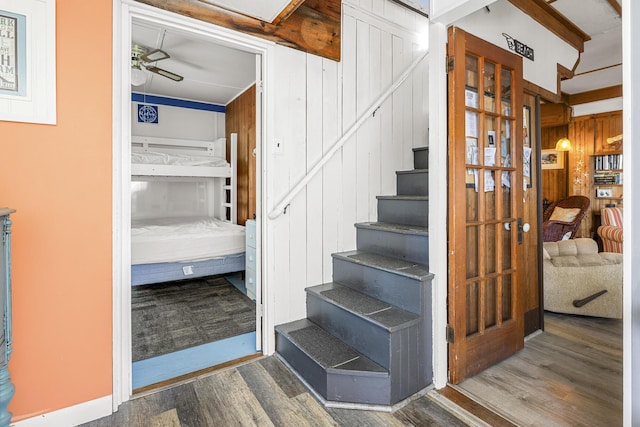 stairway featuring ceiling fan, wood finished floors, and wooden walls