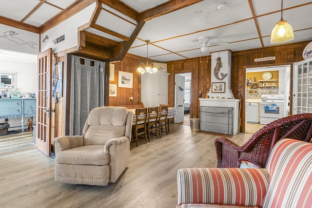 living room with wood walls, a chandelier, a ceiling fan, and light wood-style flooring