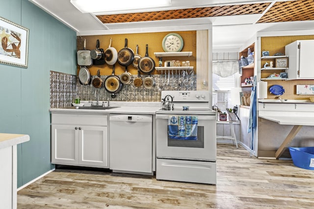 kitchen with white appliances, light wood-style flooring, white cabinets, and a sink