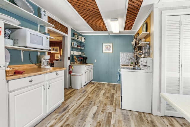 clothes washing area with washer / clothes dryer, wooden walls, light wood-style floors, and a sink