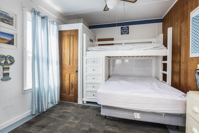 bedroom with wooden walls, multiple windows, and a ceiling fan