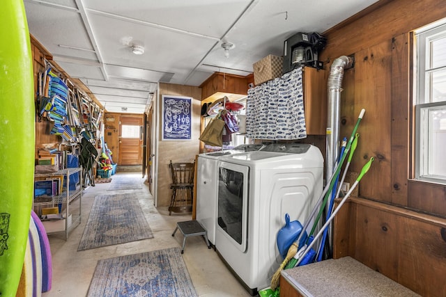 laundry room featuring wood walls, plenty of natural light, and independent washer and dryer