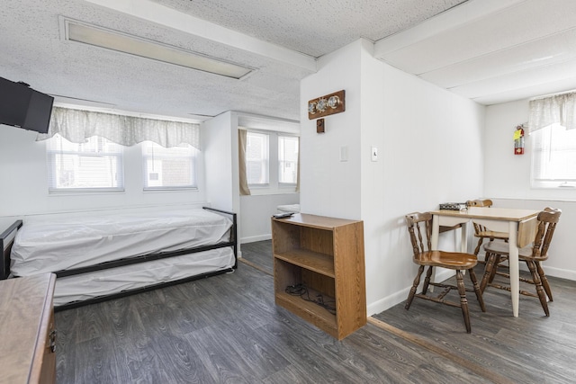 bedroom with wood finished floors, a textured ceiling, and baseboards