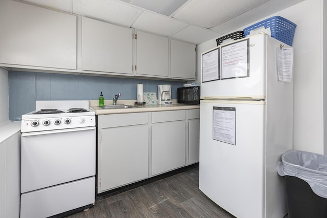 kitchen with white appliances, a sink, dark wood finished floors, light countertops, and white cabinets