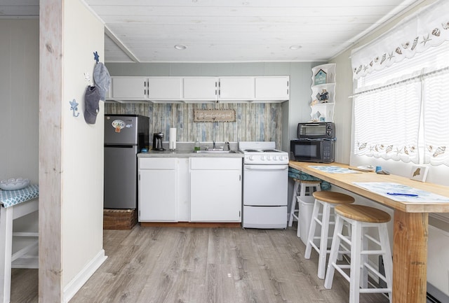 kitchen with white range oven, freestanding refrigerator, black microwave, a sink, and light wood-style floors