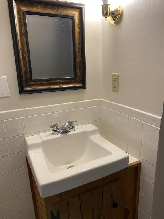 bathroom featuring tile walls, vanity, and a wainscoted wall