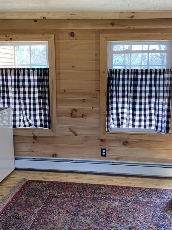 detailed view of wooden walls, baseboard heating, and wood finished floors