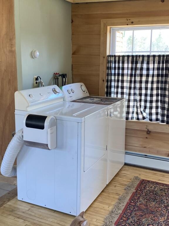 laundry area featuring washer and dryer, light wood-style flooring, and baseboard heating