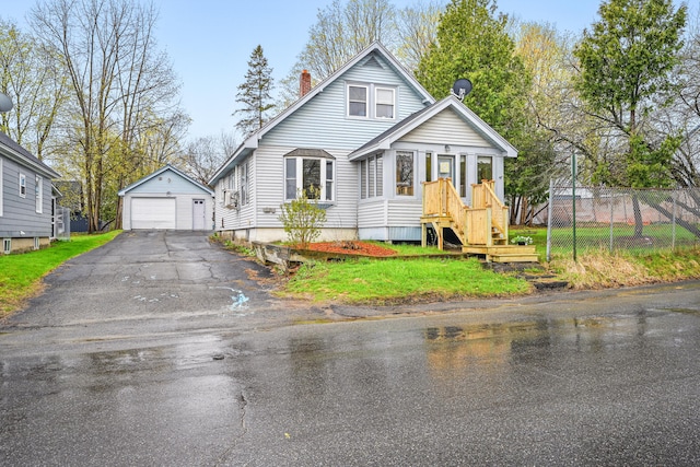 bungalow with a garage, a chimney, asphalt driveway, an outdoor structure, and fence