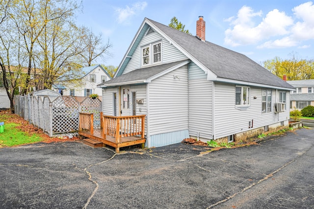 view of property exterior featuring roof with shingles, fence, a chimney, and cooling unit