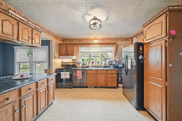 kitchen with appliances with stainless steel finishes, brown cabinets, dark countertops, and light flooring
