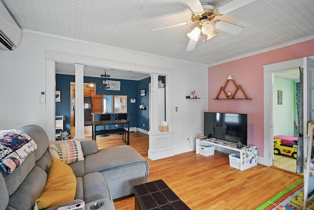 living area featuring decorative columns, an AC wall unit, wood finished floors, a ceiling fan, and ornamental molding