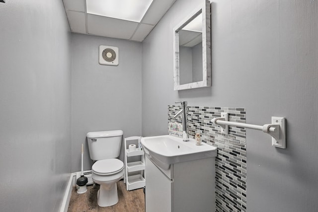 half bathroom with wood finished floors, toilet, vanity, and baseboards