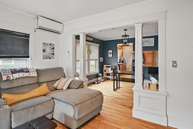 living room featuring decorative columns, a wall mounted AC, light wood finished floors, and ornamental molding