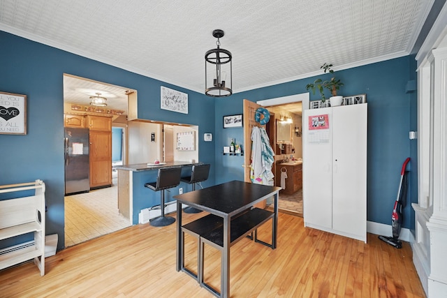 dining space featuring light wood finished floors, ornamental molding, and baseboards