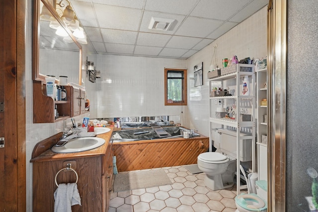 bathroom featuring a drop ceiling, toilet, tile patterned flooring, and vanity